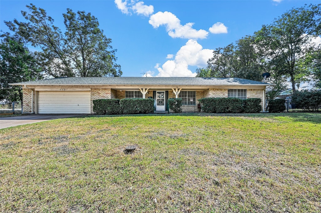 ranch-style home with a garage and a front lawn