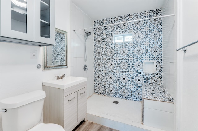 bathroom with vanity, a tile shower, wood-type flooring, and toilet