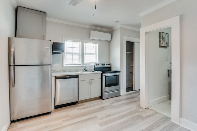 kitchen with light hardwood / wood-style flooring, a wall unit AC, stainless steel appliances, and crown molding