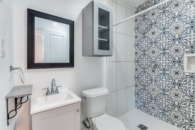 bathroom featuring vanity, toilet, and a tile shower