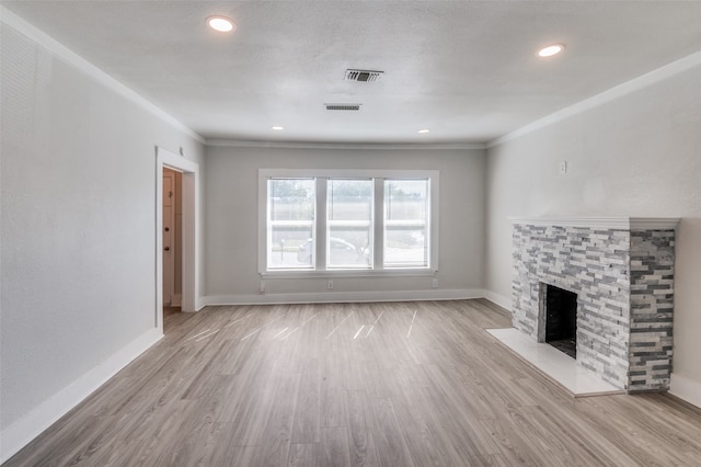 unfurnished living room featuring light hardwood / wood-style floors, a stone fireplace, and ornamental molding