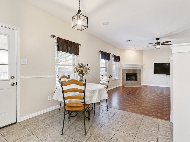 dining area featuring light parquet floors, a fireplace, and ceiling fan