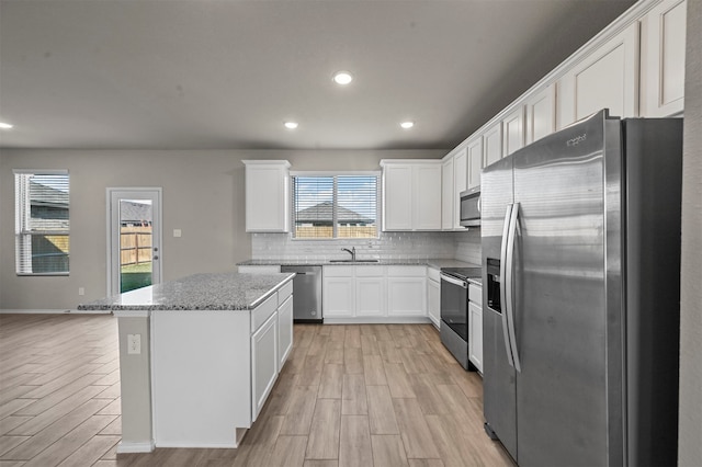 kitchen featuring a center island, appliances with stainless steel finishes, white cabinetry, and plenty of natural light