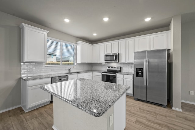 kitchen featuring sink, a center island, white cabinetry, stainless steel appliances, and light hardwood / wood-style flooring