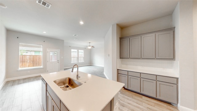 kitchen featuring sink, a kitchen island with sink, light wood-type flooring, and a healthy amount of sunlight