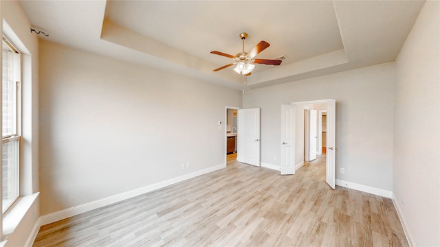 spare room featuring ceiling fan, a raised ceiling, and light hardwood / wood-style flooring