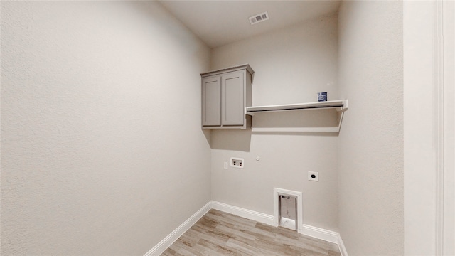 clothes washing area with hookup for a washing machine, light wood-type flooring, gas dryer hookup, electric dryer hookup, and cabinets