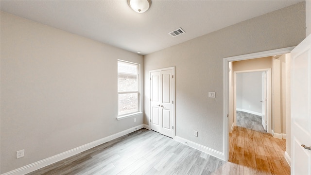 unfurnished bedroom with light hardwood / wood-style flooring and a closet