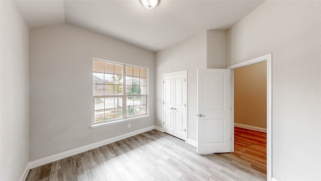 unfurnished bedroom featuring a closet, lofted ceiling, and light wood-type flooring