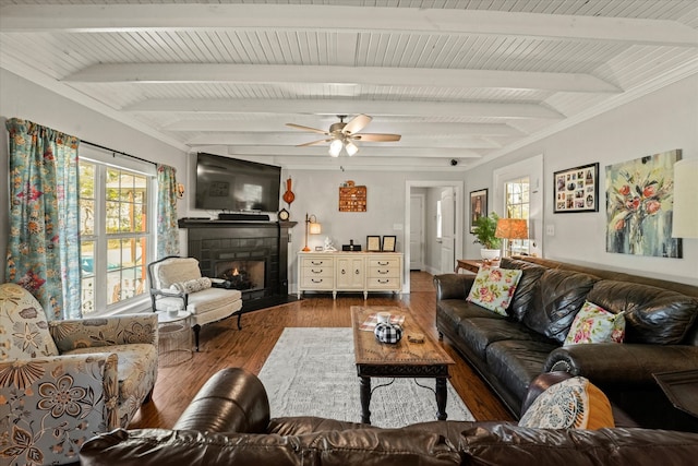 living room featuring hardwood / wood-style flooring, a fireplace, ceiling fan, and beamed ceiling