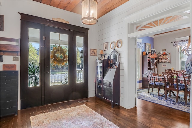 entryway with wooden walls, dark hardwood / wood-style floors, wood ceiling, and a wealth of natural light