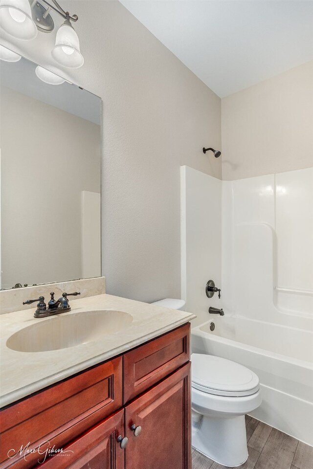 full bathroom with vanity, toilet, wood-type flooring, and bathing tub / shower combination