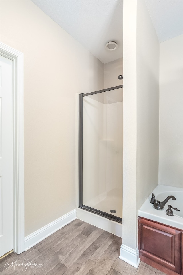 bathroom with hardwood / wood-style floors and separate shower and tub