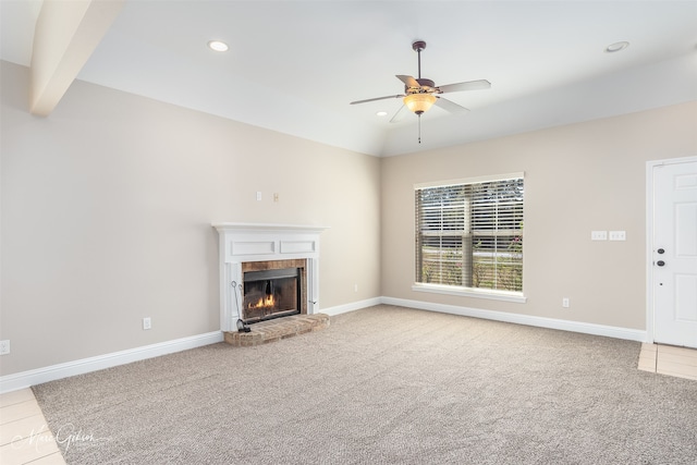 unfurnished living room with ceiling fan, beam ceiling, a brick fireplace, and light colored carpet