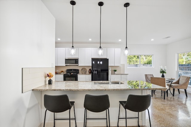 kitchen featuring light stone counters, black appliances, white cabinetry, and kitchen peninsula