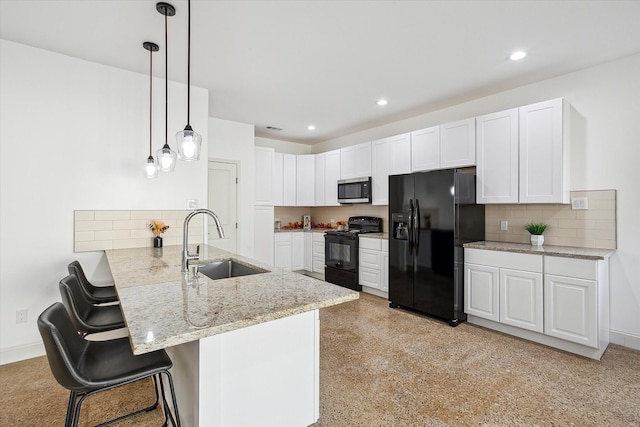 kitchen featuring black appliances, a sink, a peninsula, white cabinetry, and a breakfast bar