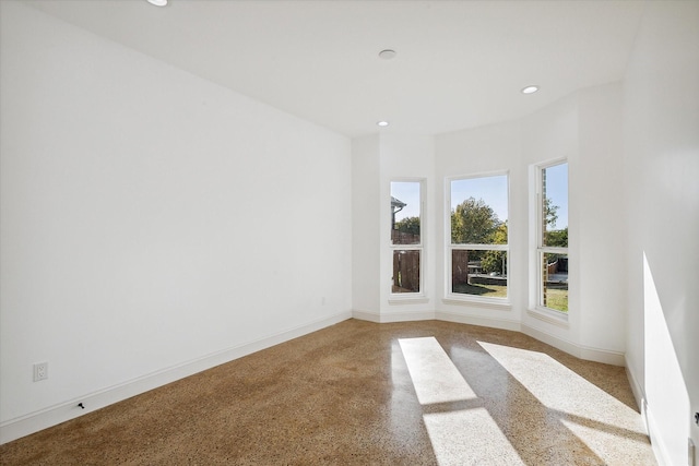 spare room with dark speckled floor, recessed lighting, and baseboards