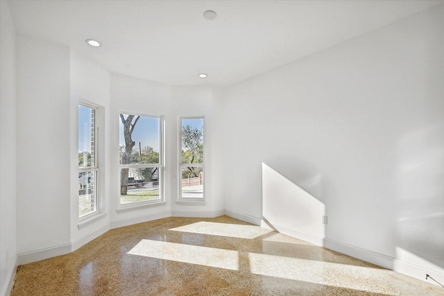 spare room with baseboards, speckle patterned floor, and recessed lighting