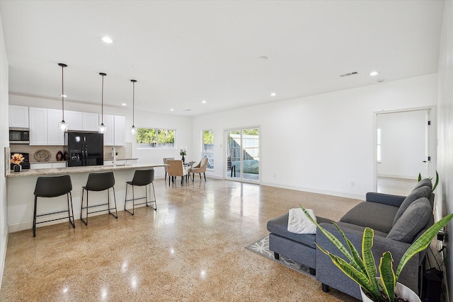 living room featuring dark aggregate flooring, recessed lighting, and baseboards
