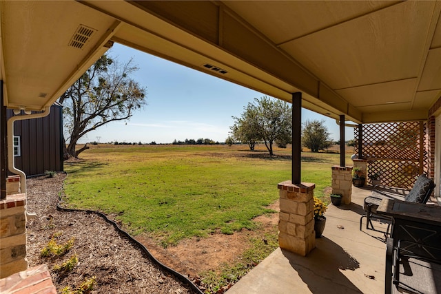 view of yard with a rural view and a patio area