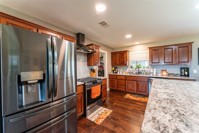 kitchen with wall chimney range hood, appliances with stainless steel finishes, sink, dark wood-type flooring, and light stone counters