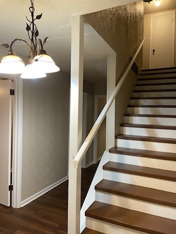 stairway featuring hardwood / wood-style flooring and an inviting chandelier