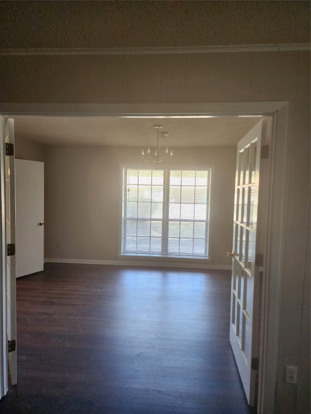 empty room with dark wood-type flooring and a notable chandelier