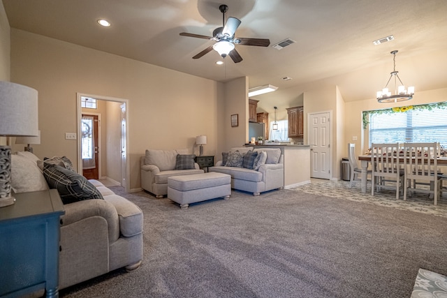 carpeted living room with ceiling fan with notable chandelier and high vaulted ceiling