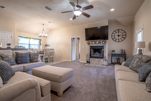 carpeted living room with a tile fireplace, lofted ceiling, and ceiling fan with notable chandelier