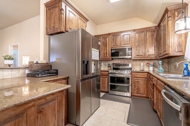 kitchen with tasteful backsplash, sink, hanging light fixtures, light tile patterned floors, and stainless steel appliances