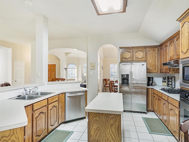 kitchen with light tile patterned floors, stainless steel appliances, under cabinet range hood, and a sink