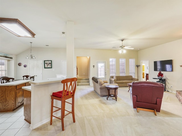 living area featuring stairway, light tile patterned floors, vaulted ceiling, light carpet, and ceiling fan with notable chandelier