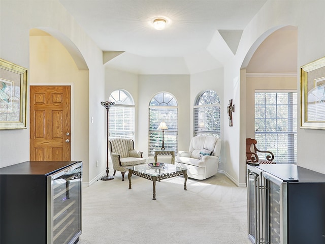 sitting room featuring light carpet, wine cooler, and ornamental molding