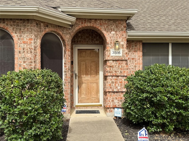 property entrance with brick siding and roof with shingles