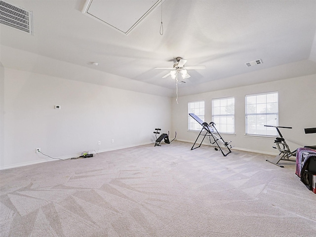 exercise area featuring visible vents, light colored carpet, attic access, and ceiling fan