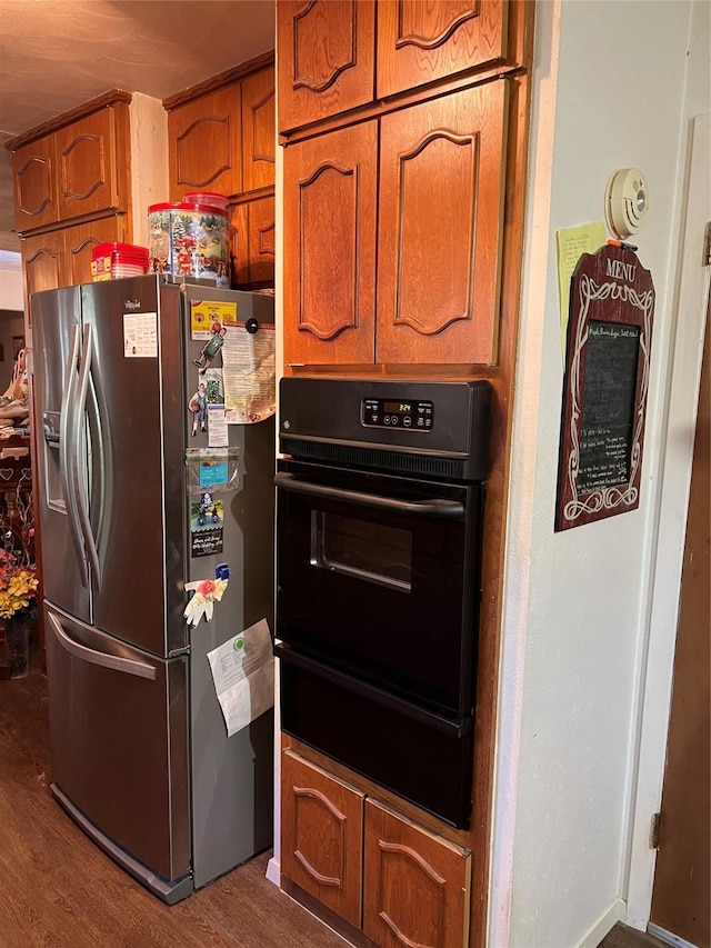 kitchen with oven, wood-type flooring, and stainless steel fridge with ice dispenser