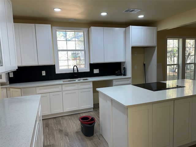 kitchen with white cabinets, sink, light hardwood / wood-style flooring, and black electric cooktop