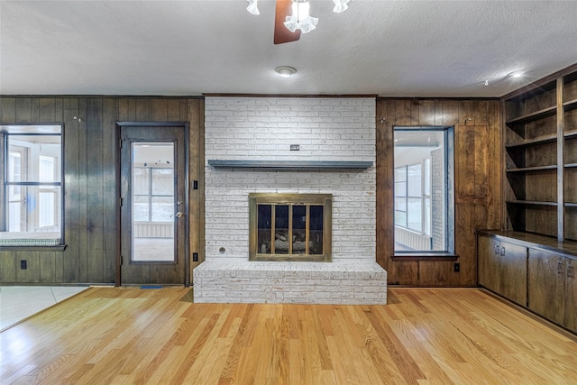 unfurnished living room with wood walls, light hardwood / wood-style floors, and a healthy amount of sunlight