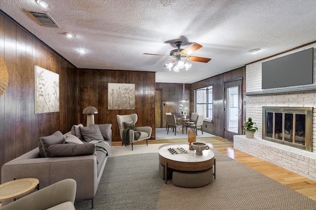 living room featuring a fireplace, a textured ceiling, and wooden walls