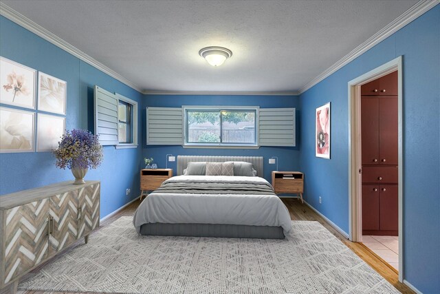 bedroom featuring crown molding, wood-type flooring, and a textured ceiling