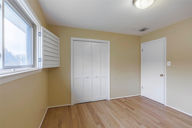 unfurnished bedroom with a closet and light hardwood / wood-style floors