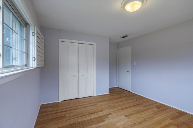 unfurnished bedroom with light hardwood / wood-style flooring and a closet