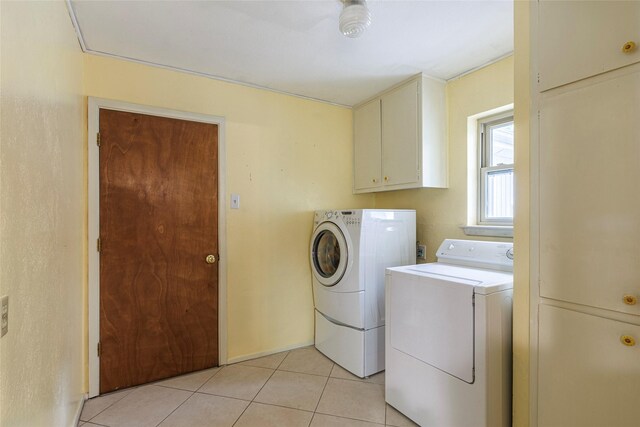 clothes washing area with washer and clothes dryer, light tile patterned flooring, and cabinets