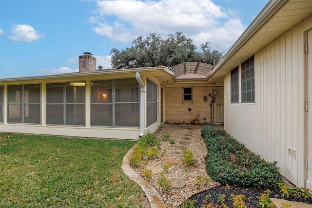 rear view of house featuring a sunroom and a yard