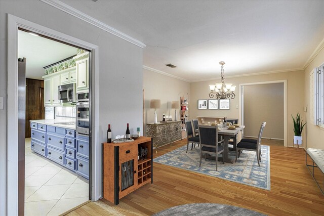 dining area with a chandelier, light hardwood / wood-style flooring, and ornamental molding