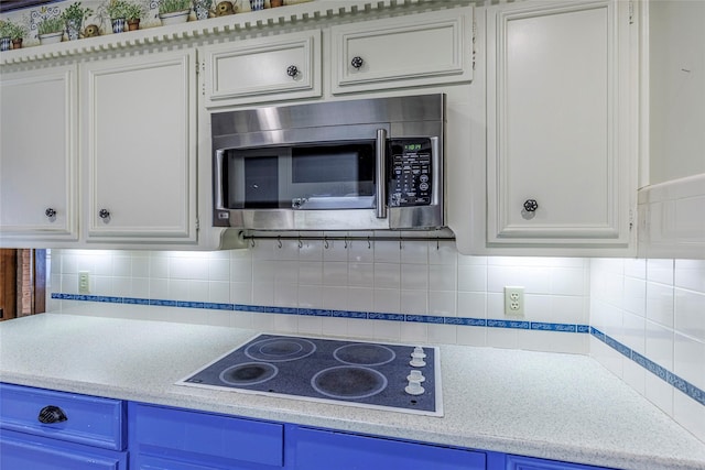 kitchen with decorative backsplash, white cabinetry, blue cabinets, and electric stovetop