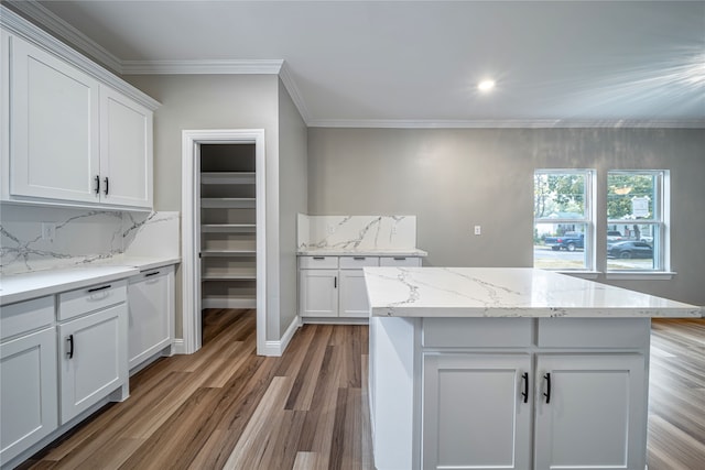 kitchen featuring hardwood / wood-style floors, crown molding, a center island, white cabinetry, and light stone counters