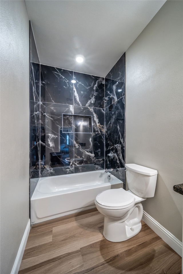 bathroom featuring tiled shower / bath, hardwood / wood-style floors, and toilet