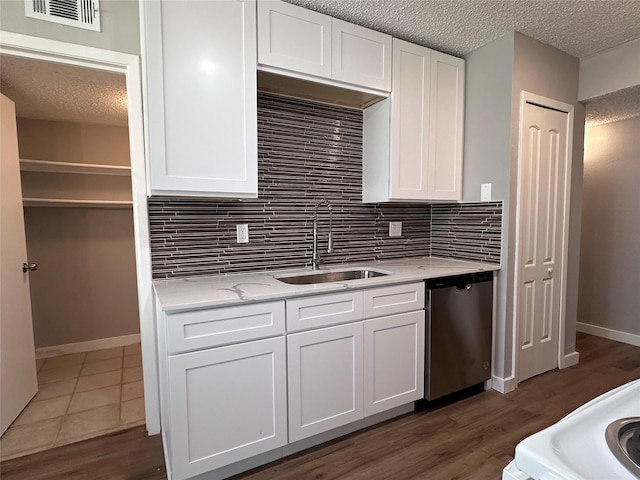 kitchen featuring white cabinetry, sink, light stone counters, stainless steel dishwasher, and decorative backsplash