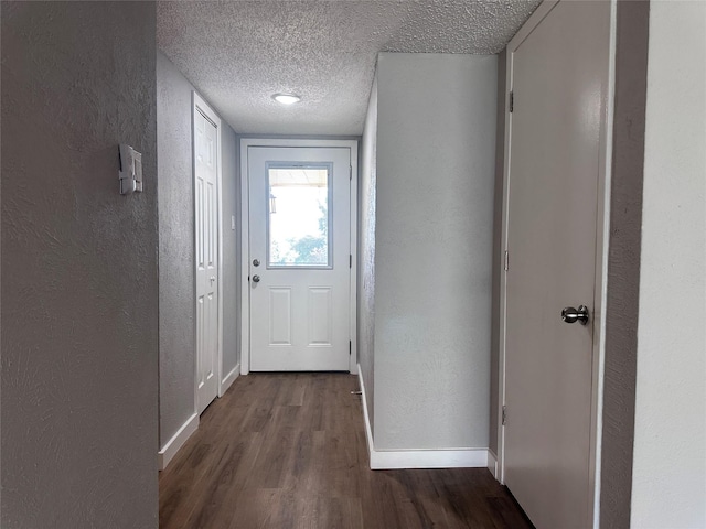 doorway with dark wood-type flooring and a textured ceiling